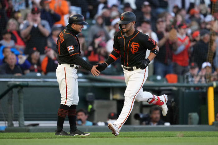 SF Giants designated hitter Michael Conforto (right) is congratulated by third base coach Mark Hallberg (left) after hitting a home run against the Texas Rangers during the fourth inning at Oracle Park. (2023)
